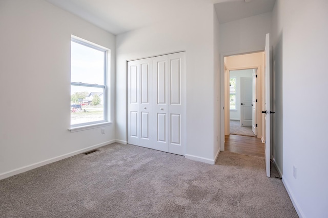 unfurnished bedroom with light carpet and a closet