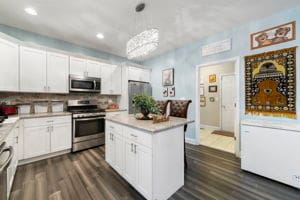 kitchen with stainless steel appliances, a kitchen island, dark hardwood / wood-style flooring, decorative light fixtures, and white cabinets