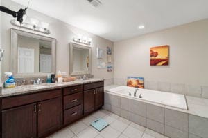 bathroom featuring vanity, tile patterned flooring, and a relaxing tiled tub