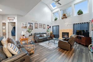 living room with hardwood / wood-style floors, ceiling fan, a fireplace, and high vaulted ceiling