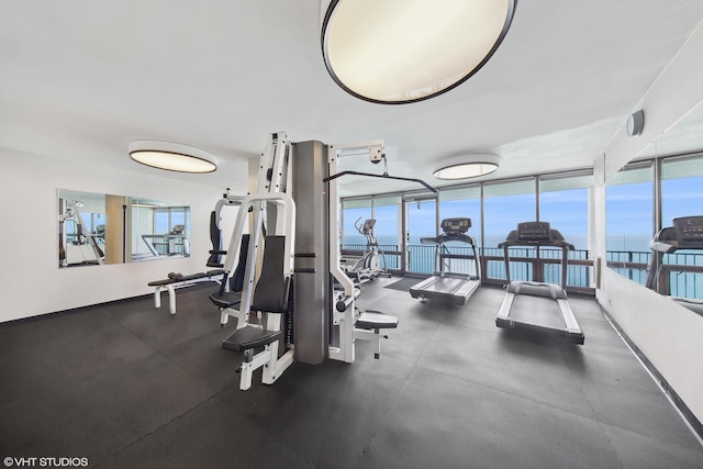 workout area with floor to ceiling windows and a water view