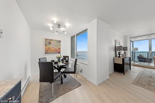 dining room with light hardwood / wood-style floors, an inviting chandelier, baseboard heating, and a water view