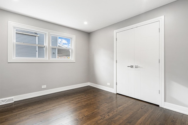 unfurnished bedroom with a closet and dark hardwood / wood-style flooring