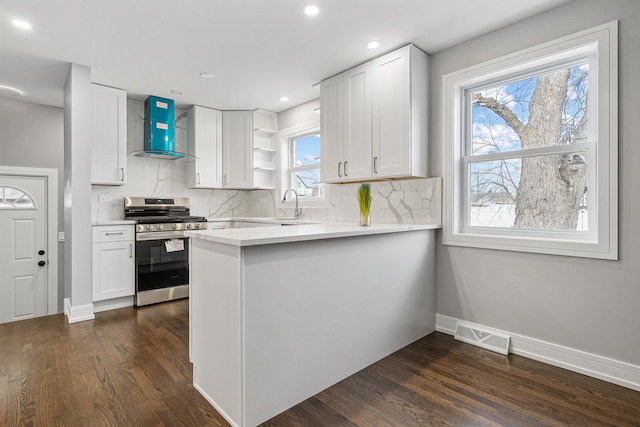 kitchen featuring stainless steel range, white cabinetry, and wall chimney range hood