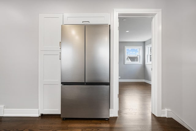 kitchen with stainless steel fridge, white cabinetry, and dark wood-type flooring