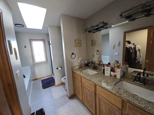 full bathroom with a skylight, vanity, plus walk in shower, tile patterned flooring, and toilet