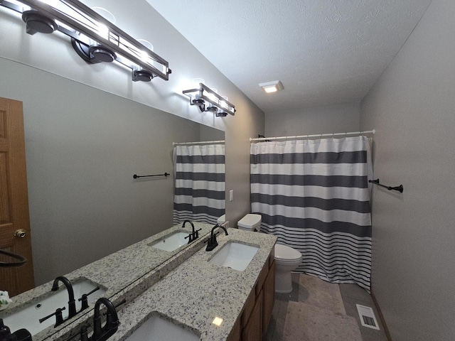 bathroom with vanity, toilet, a textured ceiling, and walk in shower