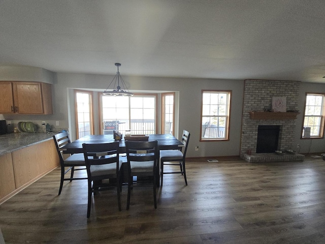 dining area with a textured ceiling, a healthy amount of sunlight, dark hardwood / wood-style flooring, and a fireplace