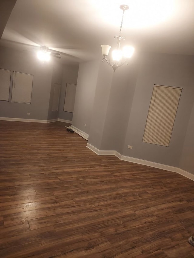 spare room featuring an inviting chandelier and dark wood-type flooring