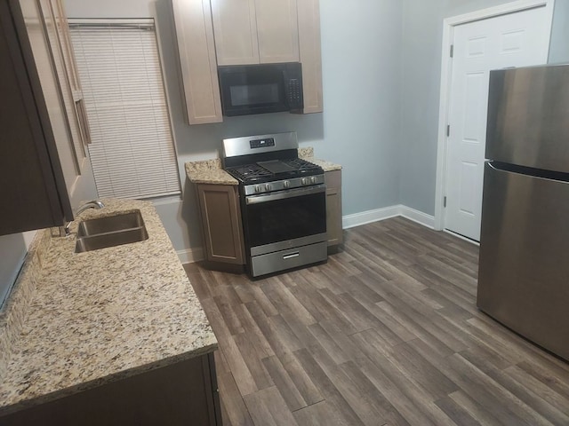 kitchen with dark hardwood / wood-style flooring, sink, light stone countertops, and stainless steel appliances