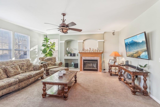 living room featuring a tile fireplace, ceiling fan, and carpet