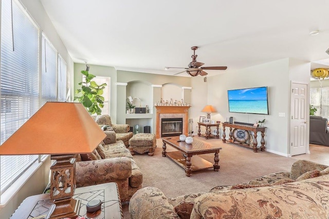 living room featuring a fireplace, light colored carpet, and ceiling fan