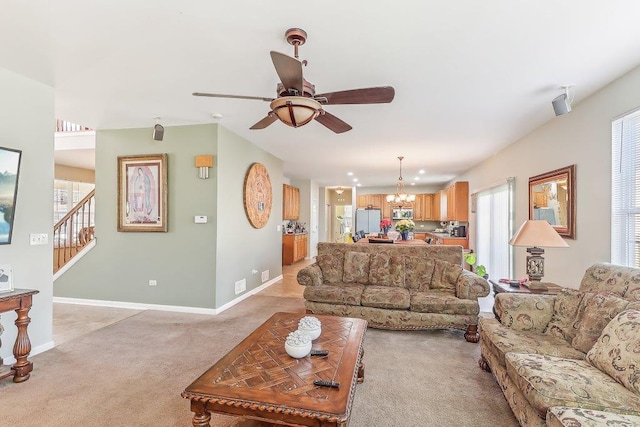 living room with ceiling fan with notable chandelier and light colored carpet