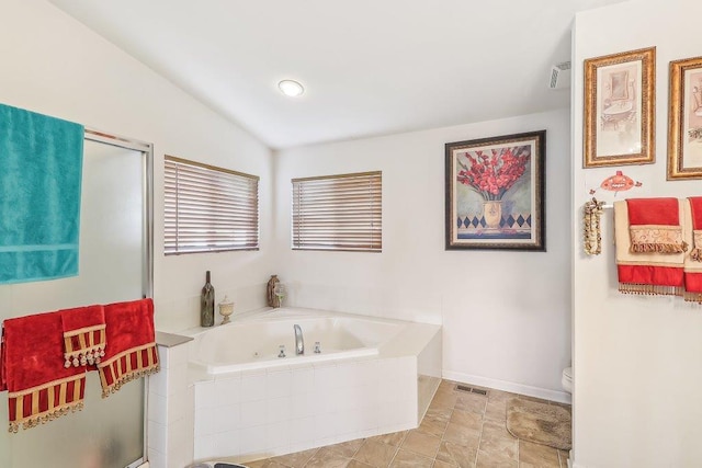 bathroom featuring vaulted ceiling, toilet, and tiled tub