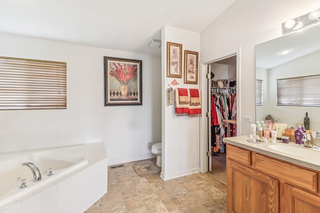 bathroom featuring vanity, toilet, and tiled tub