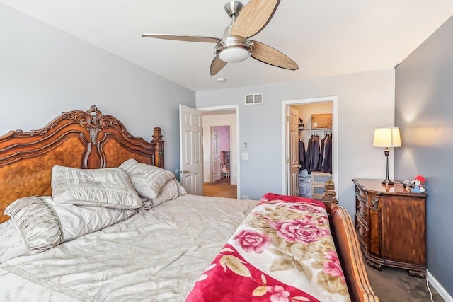 carpeted bedroom with a walk in closet, a closet, and ceiling fan