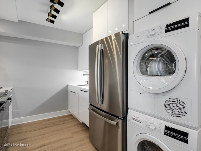 washroom featuring stacked washing maching and dryer, light hardwood / wood-style floors, and sink