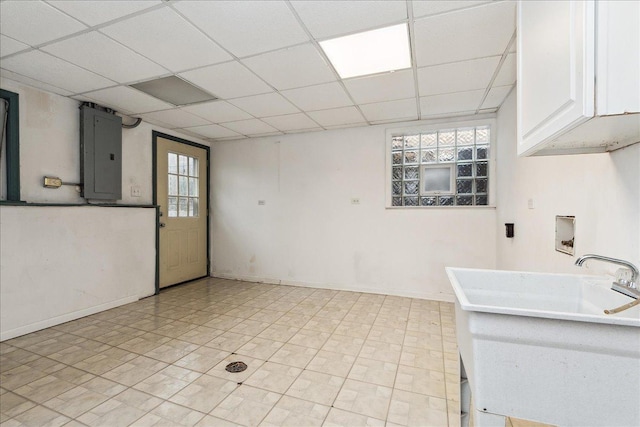 interior space with a paneled ceiling, white cabinetry, electric panel, and a healthy amount of sunlight