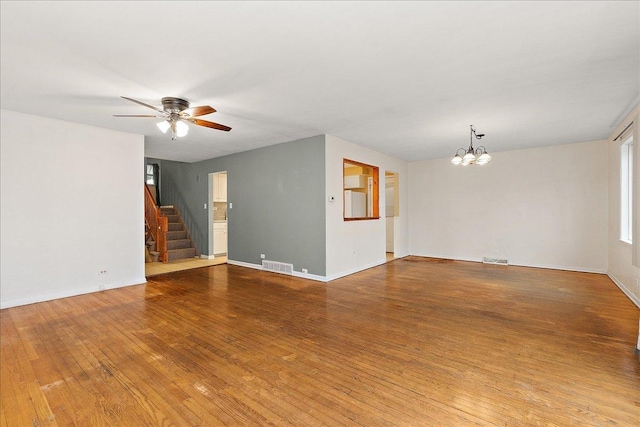 unfurnished room with ceiling fan with notable chandelier and hardwood / wood-style flooring