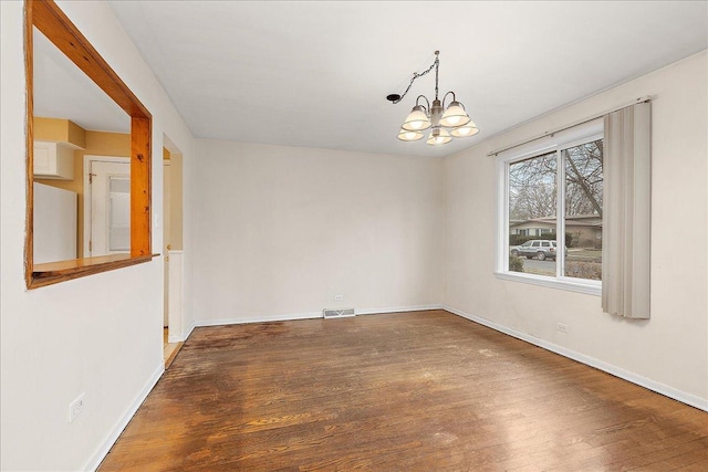 empty room with dark hardwood / wood-style floors and a notable chandelier