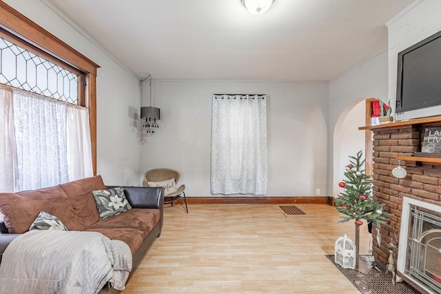 living room with a fireplace, light hardwood / wood-style floors, and ornamental molding