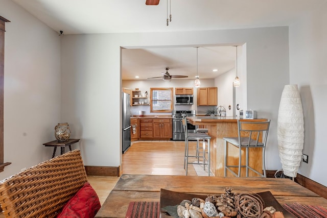 living room featuring ceiling fan, sink, and light wood-type flooring