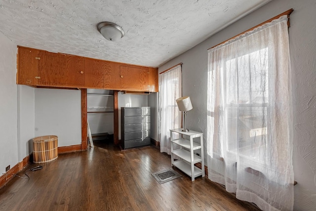 unfurnished bedroom with a textured ceiling and dark hardwood / wood-style flooring