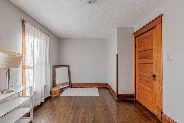 unfurnished room with a textured ceiling and dark hardwood / wood-style floors