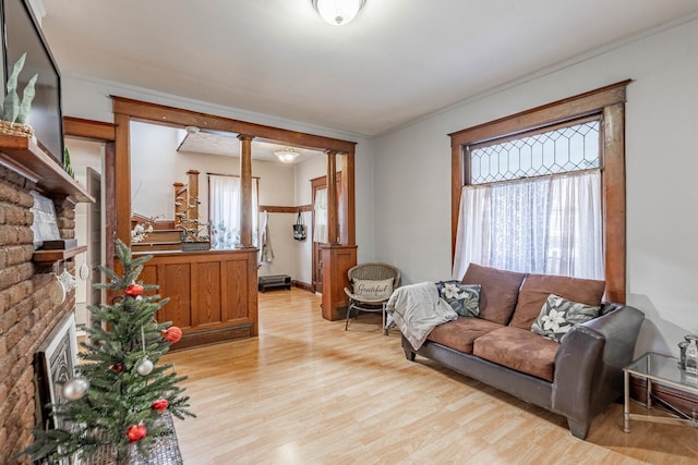 living room featuring decorative columns, light hardwood / wood-style floors, and ornamental molding