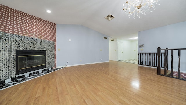 unfurnished living room featuring light wood-type flooring, a fireplace, and an inviting chandelier