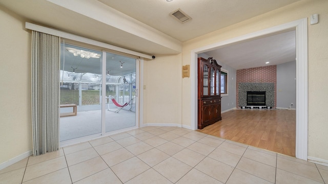 empty room with light hardwood / wood-style floors and a brick fireplace