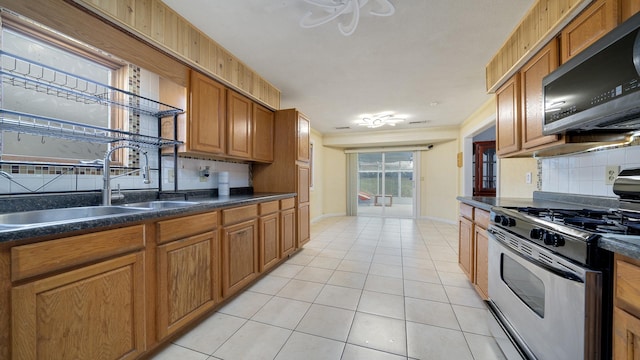 kitchen featuring decorative backsplash, sink, light tile patterned floors, and stainless steel appliances