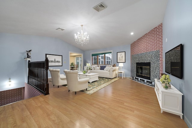 living room with a fireplace, light wood-type flooring, an inviting chandelier, and lofted ceiling