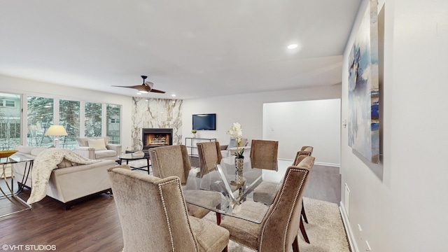 dining room featuring a fireplace, dark hardwood / wood-style flooring, and ceiling fan