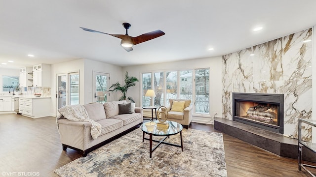 living room featuring a premium fireplace, sink, ceiling fan, and dark hardwood / wood-style floors