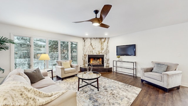 living room featuring dark hardwood / wood-style floors, ceiling fan, and a premium fireplace