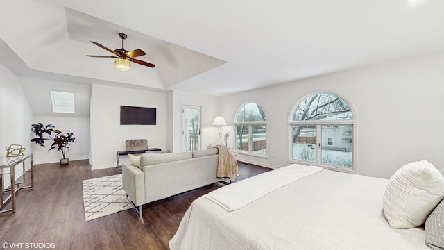 bedroom with a raised ceiling, a skylight, ceiling fan, and dark wood-type flooring