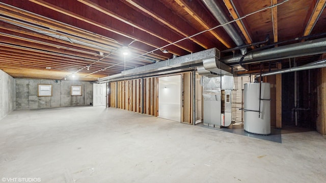 basement featuring gas water heater, heating unit, and fridge