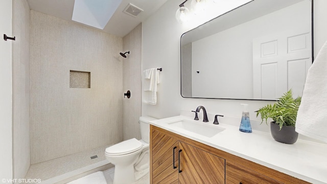 bathroom with tiled shower, vanity, and toilet