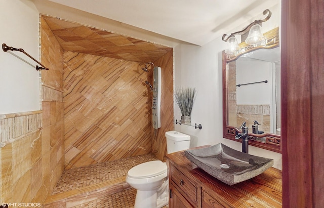 bathroom featuring a tile shower, vanity, and toilet