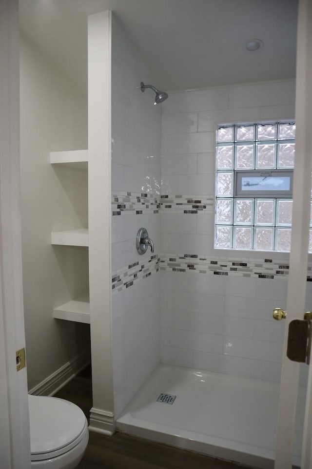 bathroom with toilet, built in features, and a tile shower