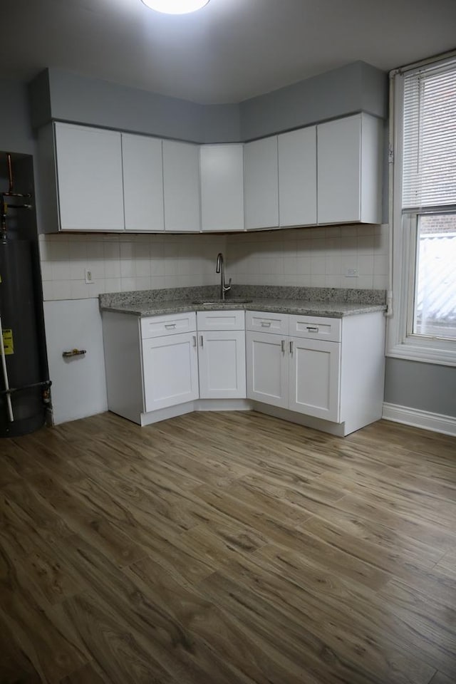 kitchen featuring white cabinetry, sink, water heater, and wood-type flooring