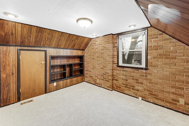 bonus room with carpet, brick wall, and vaulted ceiling