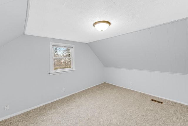 additional living space featuring a textured ceiling, carpet floors, and lofted ceiling