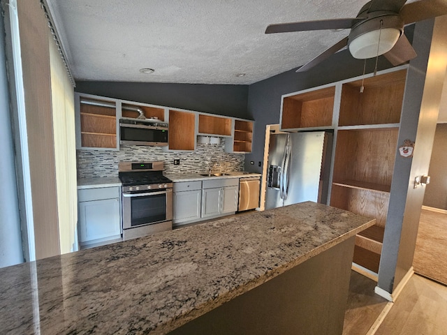 kitchen with backsplash, vaulted ceiling, ceiling fan, a textured ceiling, and appliances with stainless steel finishes