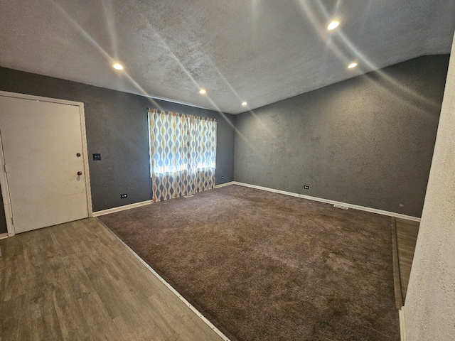 spare room with a textured ceiling, hardwood / wood-style floors, and lofted ceiling