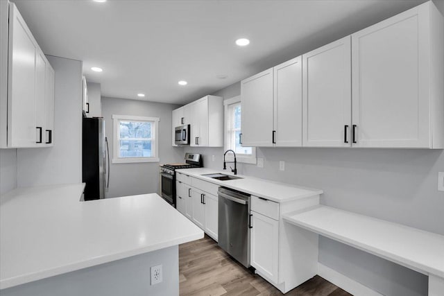 kitchen featuring white cabinets, stainless steel appliances, light hardwood / wood-style flooring, and sink