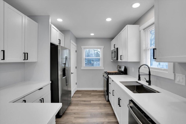 kitchen featuring sink, white cabinets, stainless steel appliances, and plenty of natural light