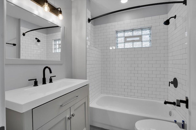 full bathroom featuring vanity, tiled shower / bath combo, and toilet