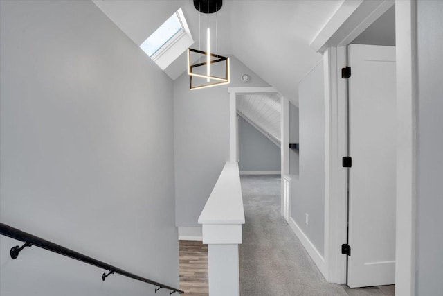 staircase with vaulted ceiling with skylight and wood-type flooring